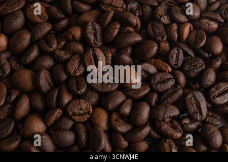 Close up image of roasted coffee beans, displaying their rich brown texture and details. Ideal for illustrating concepts related to coffee, aroma, and Stock Photo