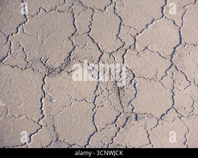 Aerial view of a cracked and patterned salt flat surface, showcasing natural formations and textures. The dry, arid landscape creates intricate vein-l Stock Photo