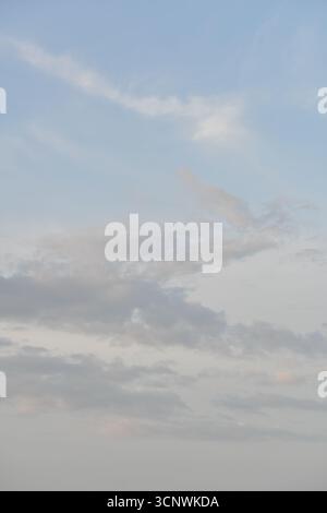 Vertical view of grey cumulus and stratocumulus clouds in a pastel blue sky Stock Photo