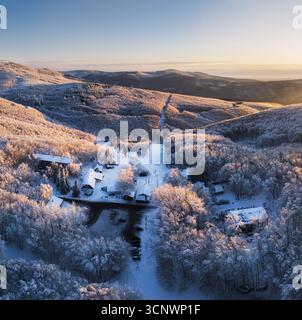 Mountain alpine village at sunset in winter landescape with snow covered forest Stock Photo