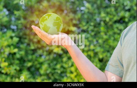 Side view of man holds a green planet Earth on a background of real nature. Symbol of sustainable development and renewable energy Stock Photo