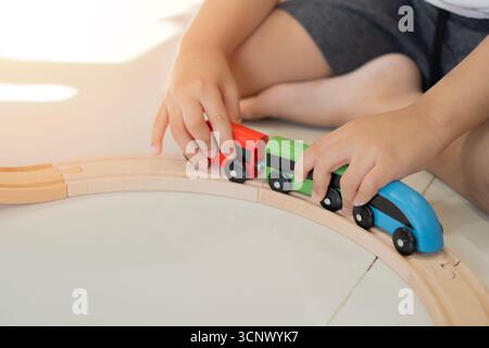 Children enjoying toy train railway concept. Toddler engaging with wooden trains. Building railway and blocks at home. Stock Photo
