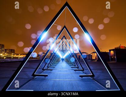 Glowing tunnel of triangular frames at night, with bokeh lights enhancing its surreal, dreamlike ambiance. Infinite possibilities and the journey Stock Photo