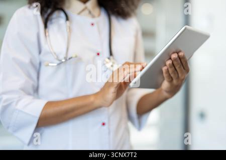 Close-up of medical professional using tablet in hospital. Focus on hands and device showing healthcare technology, indicating modern patient information management. Stock Photo