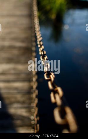 Close-up view of rusty metal chain reflecting in calm water of a serene lakeside Stock Photo