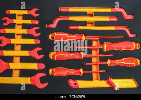 A comprehensive set of insulated tools, including wrenches and screwdrivers, designed for safe electrical work, with vibrant orange and yellow handles Stock Photo
