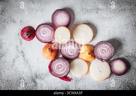 Flat lay of sliced red and yellow onions arranged on textured light background. Natural food composition with vibrant rings and earthy colors, perfect Stock Photo