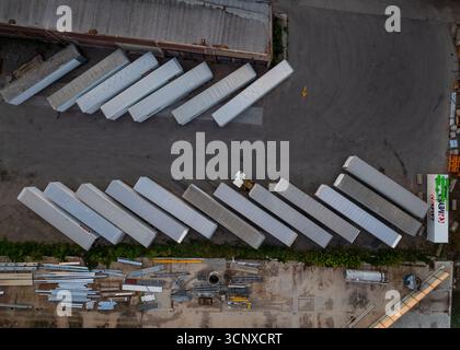 Aerial view of diagonally arranged freight trailers on pavement in an industrial area, creating a geometric top-down view of light and dark. Appleton, Wisconsin, United States. Stock Photo