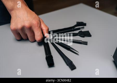 Technician holding set of specialized cleaning tools, including brushes, tweezers, blower, designed for meticulous computer maintenance and repair. Stock Photo