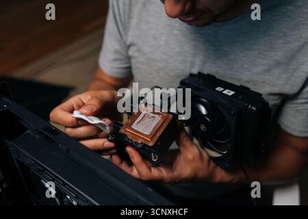 Precise computer maintenance involving cleaning processor cooling system, wiping delicate electronic components with white microfiber cloth for peak Stock Photo