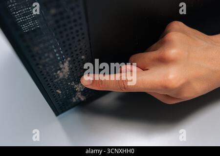 Close-up of technician pointing at thick layer of dust on computer air vents, emphasizing importance of regular cleaning and maintenance to avoid Stock Photo