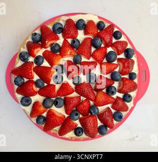 Overhead view of homemade sponge cake decorated with cream strawberries and blueberries Stock Photo