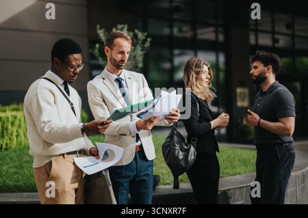Business professionals collaborating on a project outdoors near a modern office building Stock Photo