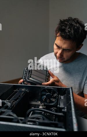 Vertical portrait of focused computer technician installing cooling radiator, carefully positioning computer hardware component during precision Stock Photo