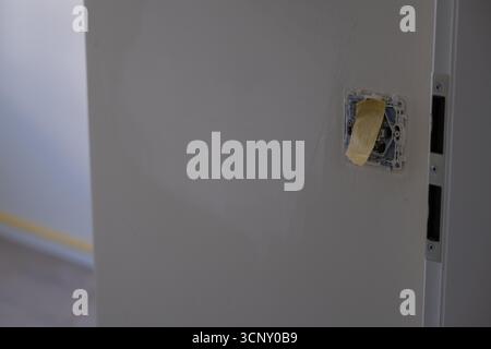 Electrical switch socket taped with protective film on a wall in progress of renovation. Suitable for illustrating construction, repair, home improvem Stock Photo