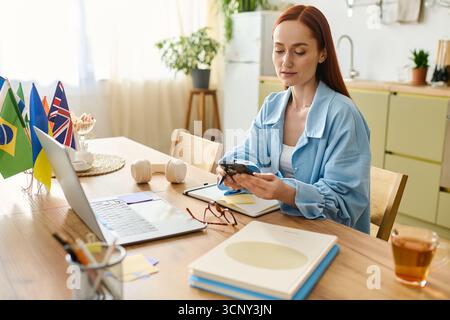 A language teacher with red hair connects with students from her home workspace using a laptop. Stock Photo
