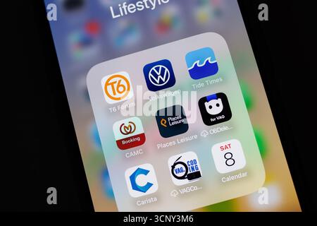 iphone Smartphone screen displaying various lifestyle apps including Volkswagen and Tide Times with app icons arranged in a folder Stock Photo