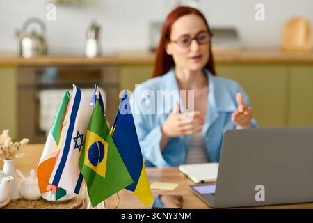A woman with red hair teaches languages remotely, engaging students through her laptop. Stock Photo