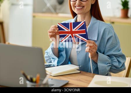 A woman with red hair teaches language lessons online, smiling as she engages students. Stock Photo