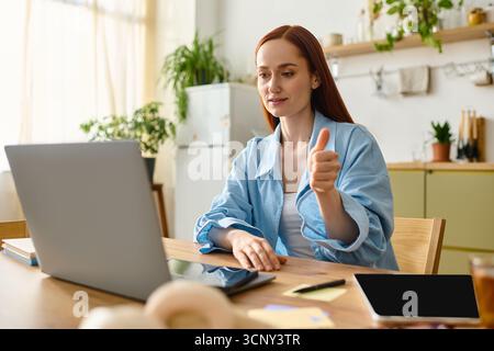 A red-haired language teacher engages online from her cozy home. Stock Photo