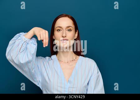 A woman with red hair teaches sign language in front of a blue background, engaging students. Stock Photo