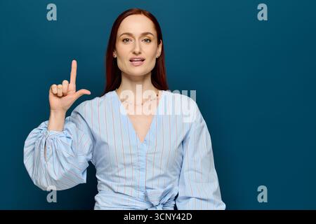 A woman with red hair teaches sign language, engaging students in a colorful setting. Stock Photo