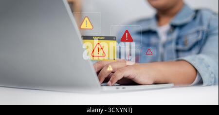 Close up of person using laptop with multiple warning alert icons on screen, concept of cybersecurity, malware, system error, online threat, data prot Stock Photo