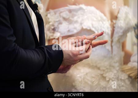 A groom places a wedding ring on his bride's finger during a wedding ceremony.  A moment of love and commitment. Stock Photo