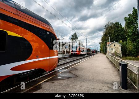 Modern Elron passenger trains at Tartu Railway Station, Estonia, with orange livery on tracks under cloudy skies at this key Baltic transport hub. Stock Photo