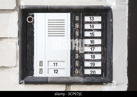 White intercom with buttons and speaker on wall. Apartment building entrance communication system. Security and access control detail. Stock Photo