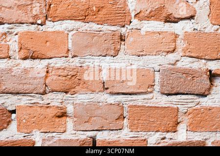 Orange brown brick wall closeup. Rough surface with natural cracks and cement. Rustic vintage background. Old construction material texture. Stock Photo
