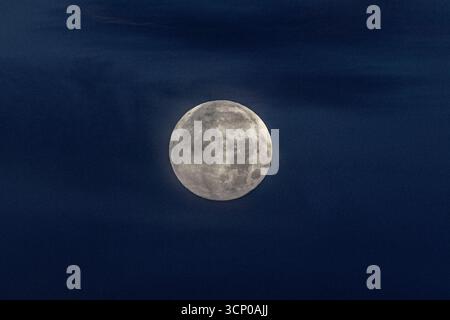 Lunar sphere: The moon glows in the dark night sky, its surface features captured in exquisite detail. Stock Photo
