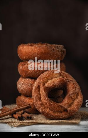 A stack of Fresh made Apple cider Donuts with one leaning on the stack against a mottled dark brown background with copy space. Stock Photo