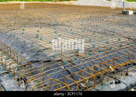 Steel rebar mesh foundation with plastic vapor barrier prepared for pouring concrete slab at a building site Stock Photo