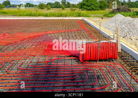 Red underfloor heating pipes laid in a reinforced concrete foundation with insulation, prepared for energy-efficient radiant floor heating system Stock Photo