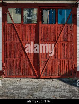 Old brown garage doors. Brownish-red wooden barn gates with small windows in upper section. Stock Photo