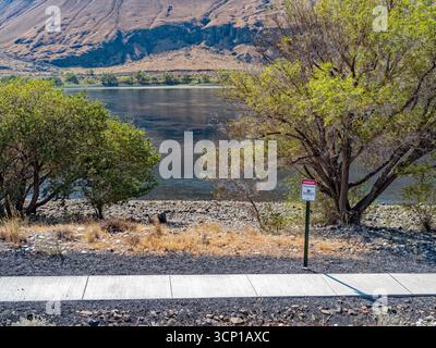 A sign by the sidewalk warns of strong currents in the Columbia River near Mattawa in Washington, USA Stock Photo