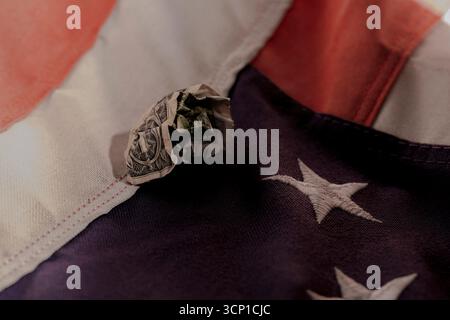 Close-up of a crumpled U.S. dollar bill placed on the American flag. Stock Photo