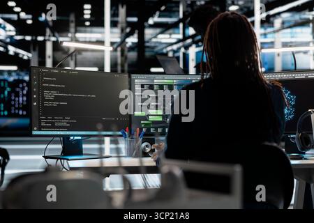 Server room programmer coding, using artificial intelligence to enhance operational efficiency and reduce downtime. Worker designs and implements AI driven solutions for data center equipment using PC Stock Photo