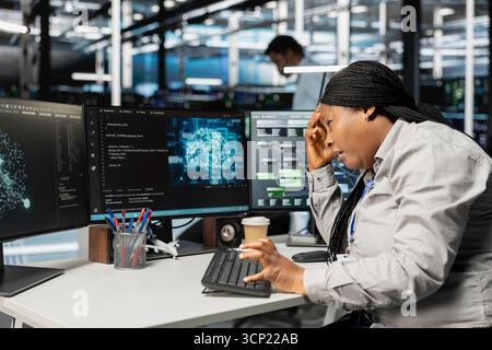 Tired engineer in pain suffering from headache while setting up data center equipment needed to run artificial intelligence. Fatigue server room worker affected by migraine using AI tools Stock Photo