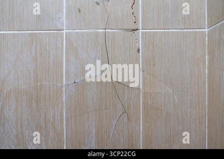 Cracked old bathroom tile with visible damage and moisture stains Stock Photo