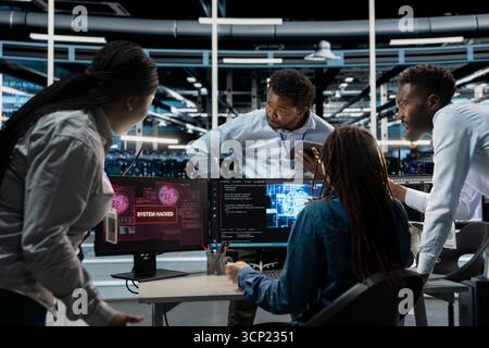 Engineering team in AI server hub work together to defend against hacker attack stealing sensitive data. Artificial intelligence data center teamworking colleagues fight virus during security breach Stock Photo