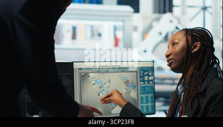 Photovoltaics factory programmer building models of renewable energy generators, presenting progress to manager. Solar panels plant developer builds safe solar cells talking with supervisor, camera B Stock Photo
