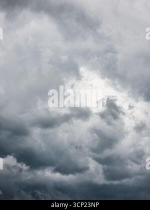 Looking up at the dramatic sky with storm clouds. Sky gradient from light grey to dark steel grey. Stock Photo