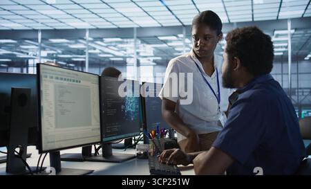 Manager taking feedback from data center engineer maintaining company network infrastructure. Team leader in server hub listening worker ensuring optimal system performance, camera A Stock Photo