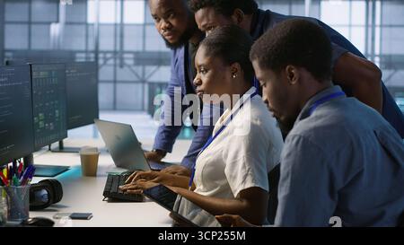Team of data center technicians maintaining company network infrastructure by configuring and troubleshooting hardware. Teamworking server hub colleagues ensuring optimal system performance, camera A Stock Photo