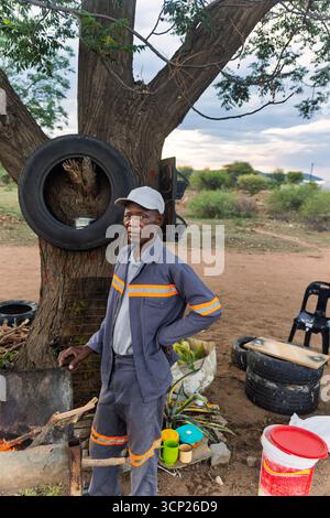 africa village, portrait of single happy african elderly man, standing on a dirt road, next to a fire Stock Photo