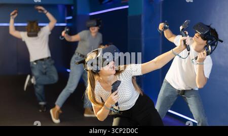 Portrait of woman using virtual reality goggles controlling joysticks standing in dark room Stock Photo