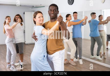 Smiling dancing people practicing movements while dancing in pairs in dance school for adults Stock Photo