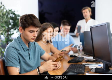 Focused young student using smartphone while studying in computer workshop Stock Photo